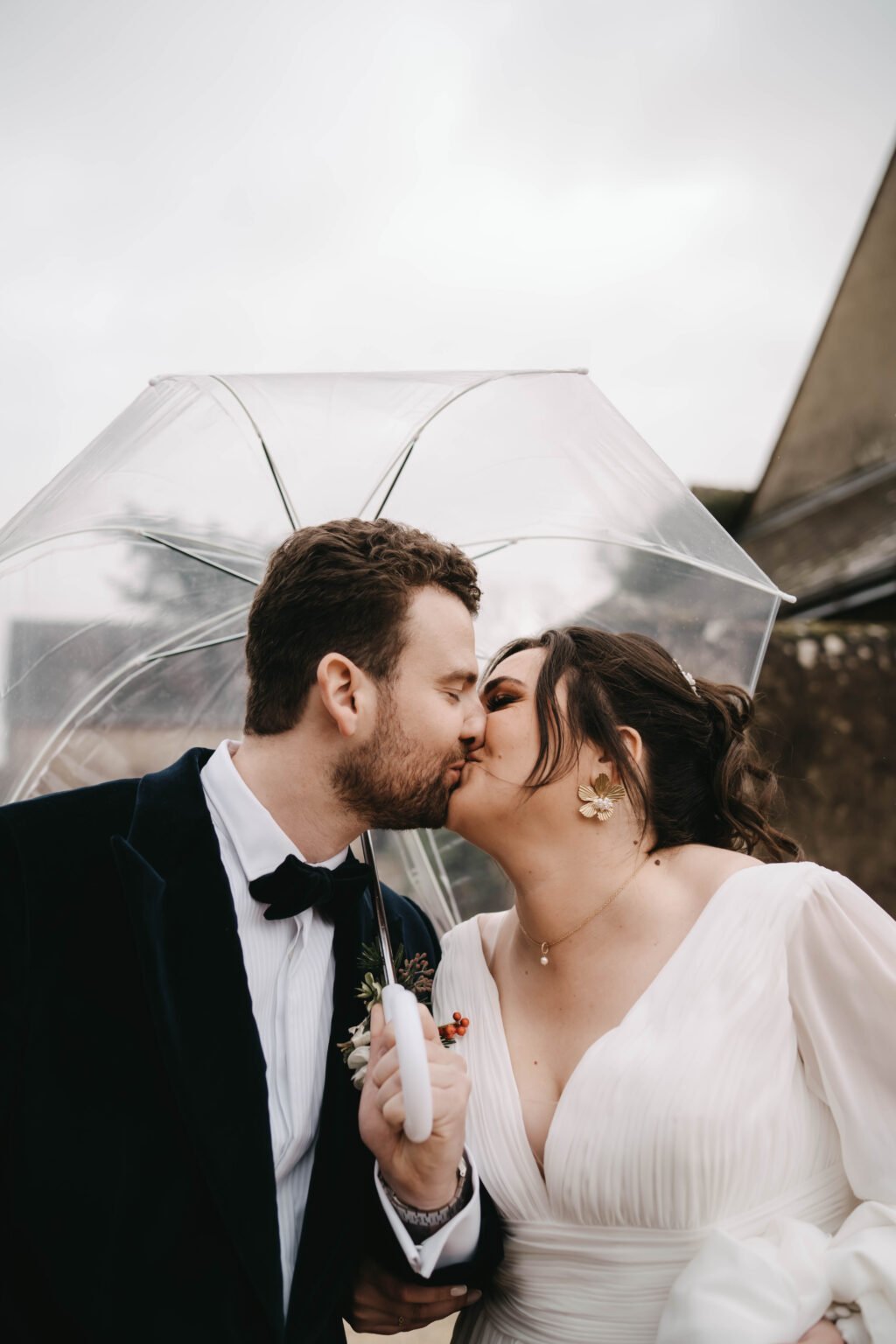 mariés s’embrassant sous parapluie mariage pluie