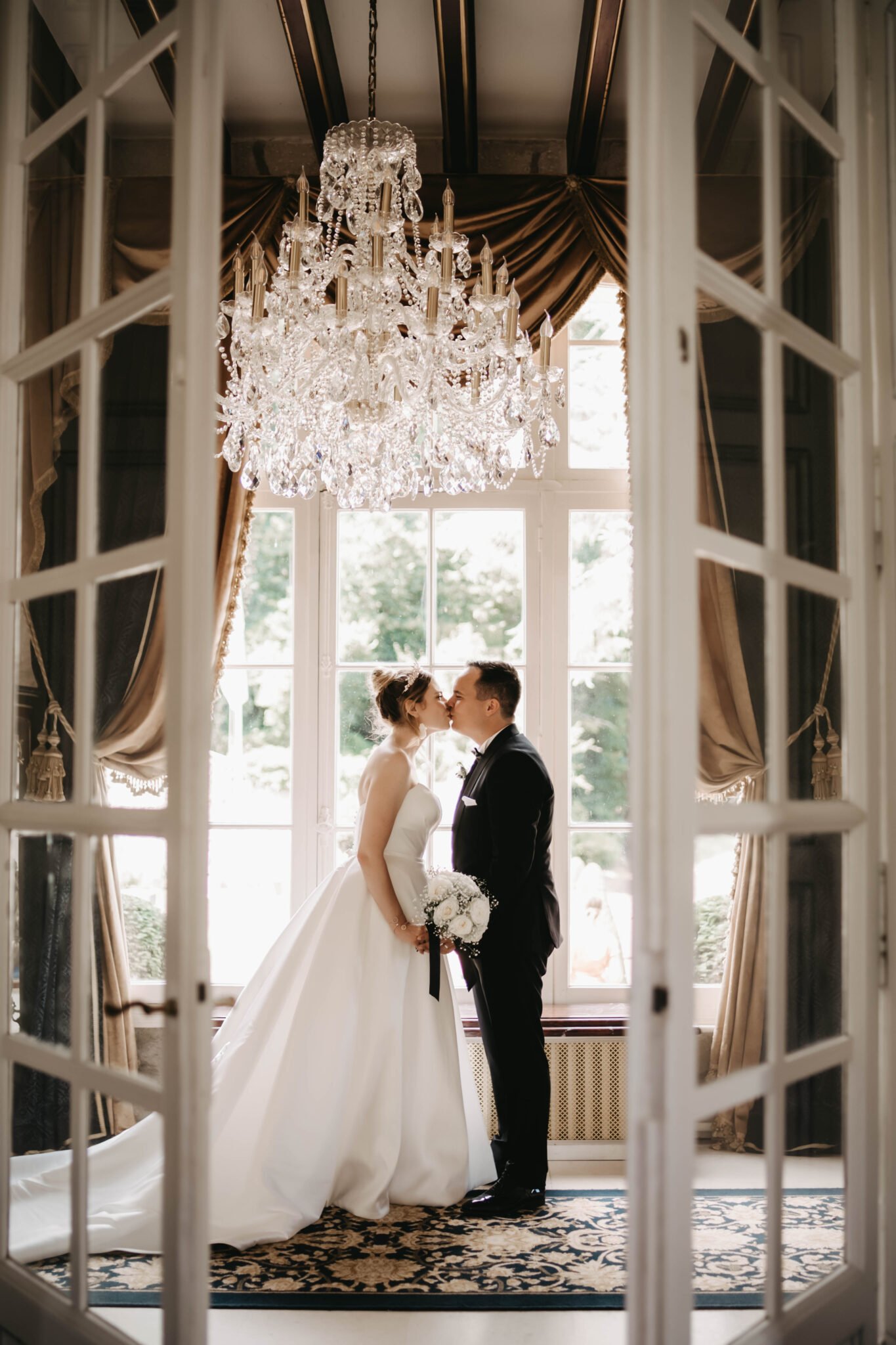 mariés qui s’embrassent dans une salle avec lustre