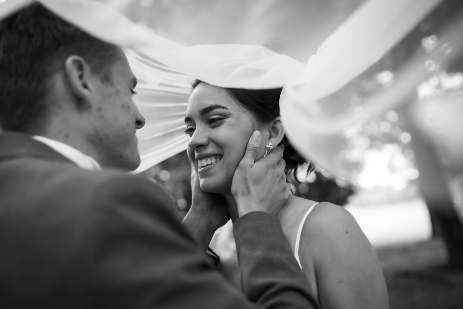 marié tenant le visage de la mariée sous son voile