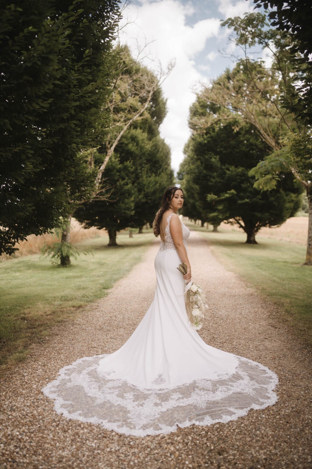 portrait de mariée dans une allée bordée d’arbres