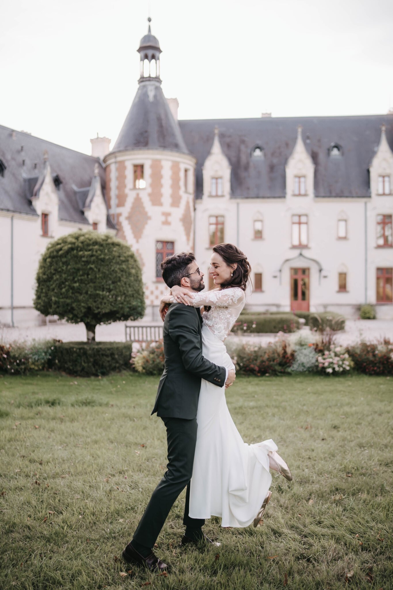 mariés qui se portent dans les bras devant un château
