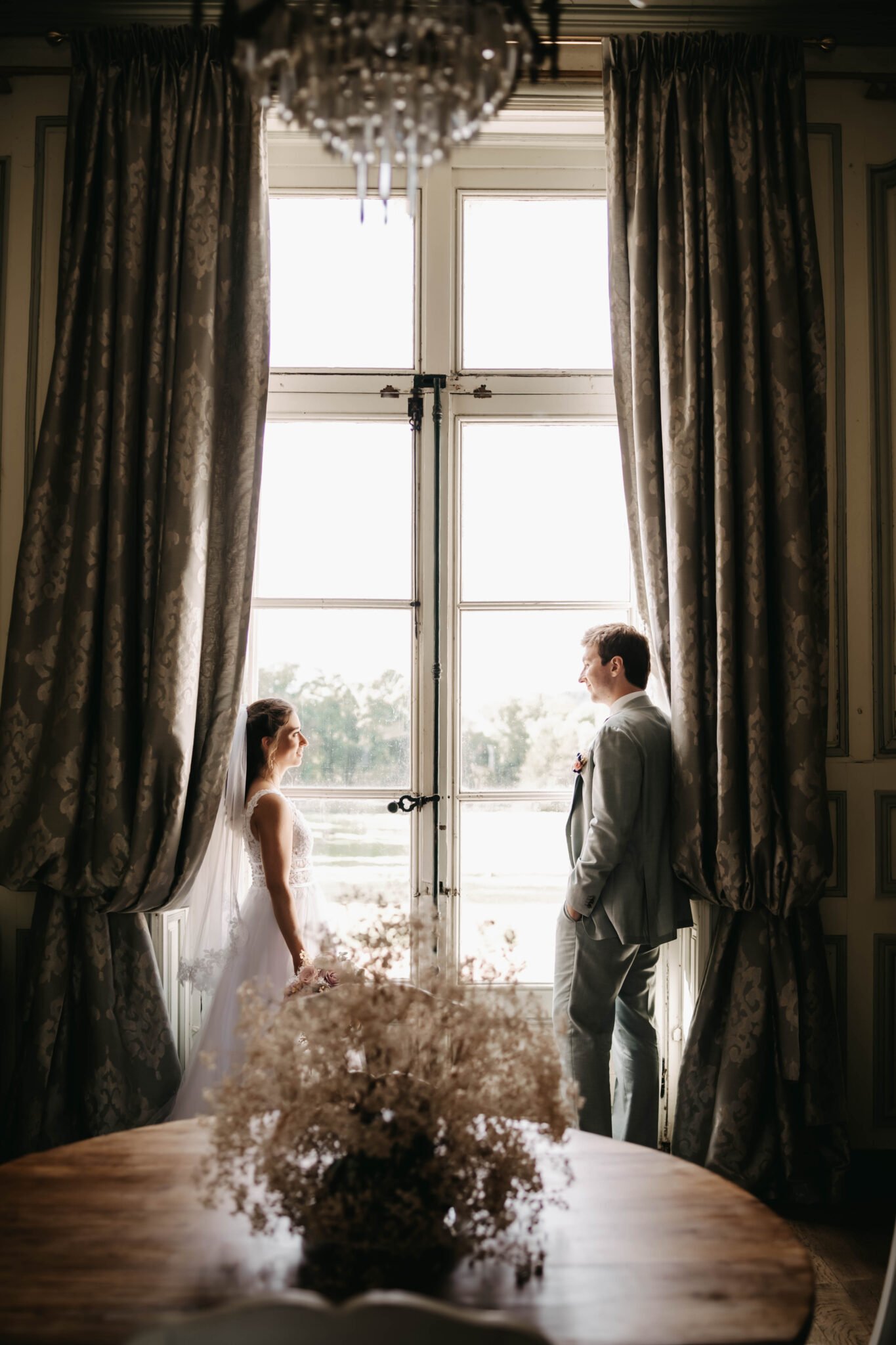 mariés face à face devant une grande fenêtre dans un château