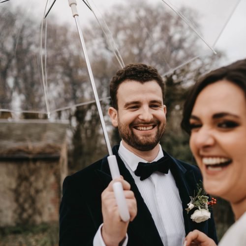portrait de mariés souriants sous un parapluie