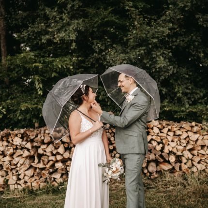 couple de mariés sous parapluie pendant un mariage en extérieur